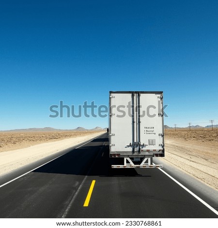 Back view of semi truck traveling down highway towards horizon under clear blue sky. Royalty-Free Stock Photo #2330768861