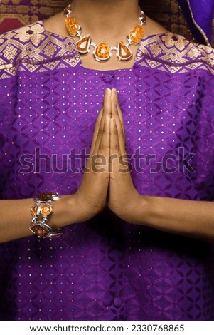 Portrait of praying African-American young adult woman wearing traditional purple African dress.