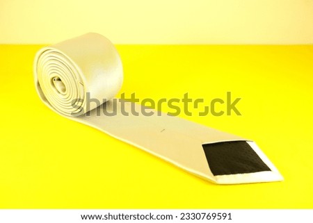 plain fabric necktie rolled isolated on yellow background close up shot single object concept nobody 