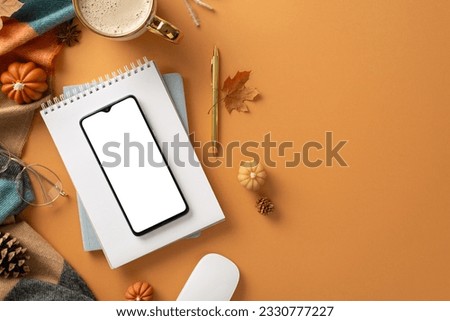 Fall-inspired workspace idea. Top view of phone, computer mouse, cup of pumpkin spice latte, planner, spectacles, warm plaid, small decorative gourds, maple leaves, orange backdrop with space for text