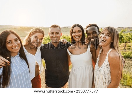 Happy multiracial friends having fun outdoor with vineyards in background - Tourist multi ethnic people smiling on camera during summer vacation - Travel, friendship and summer holidays concept Royalty-Free Stock Photo #2330777577