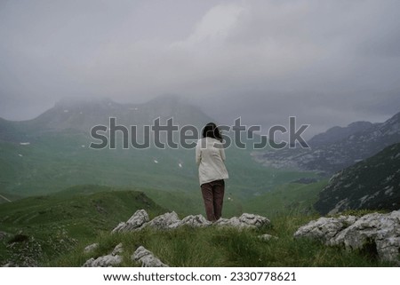 Young traveling woman in hat and stand and walking and seat on the top of the mountain cliff watching beautiful view of mountains and sky after rain on her vacation. woman travel alone.Freedom