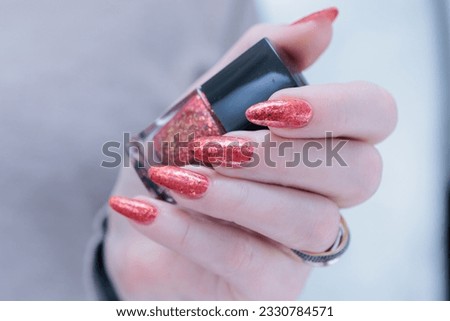 Female hand with long nails and a bright orange red manicure