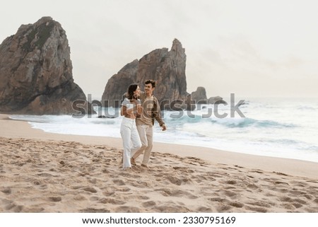 Young loving man embracing his girlfriend, couple walking on nature background, enjoying date and time together on the beach by ocean shore, full length, free space Royalty-Free Stock Photo #2330795169