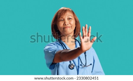 Close up shot of determined assertive nurse throwing stop hand sign, upset with work conditions. Firm BIPOC clinic employee doing halt gesturing, isolated over studio background