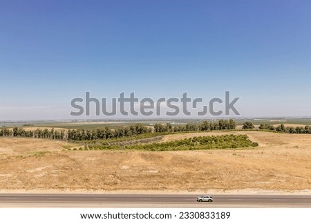 Highway in California, on which cars and trucks drive, among the yellow grass on a sunny day. American landscape from a bird's eye view. Vacation trip
