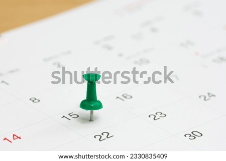Green color pin thumbtack a date on calendar or planner. Tax Day 2024 takes place on April 15. (selective focus)