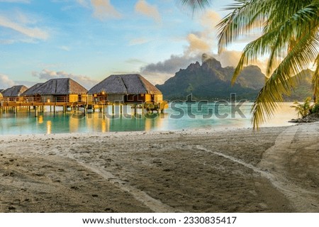 Overwater bungalows and palm trees in Bora Bora, French Polynesia; paradise on Earth Royalty-Free Stock Photo #2330835417
