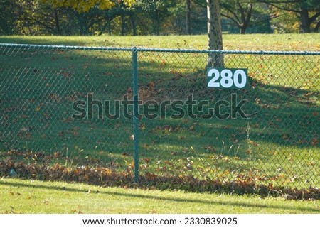 Green chain link fence in a grassy field with a sign that says 280
