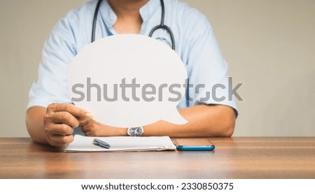Speech bubble concept. Midsection of a doctor holding a blank speech bubble while sitting at the table in the hospital. Space for text. Healthcare and advertising