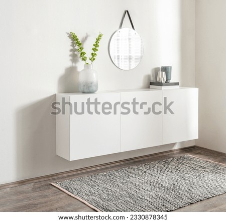 A modern interior design featuring a white wooden cabinet beneath a large wall mirror