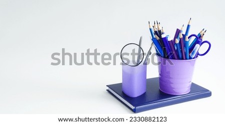 On a light background, school supplies and office accessories, pencils, felt-tip pens, a notebook, a note book, a diary in blue tones are on the table.  Space for copy text.  Concept back to school.