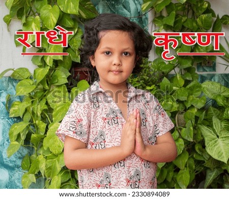 "Radhe Krishna" means the name of hindu god text word written. Indian girl smile and holding palms together in Namaste gesture on an outdoor in plant and garden background. Happy Krishna Janmashtami 