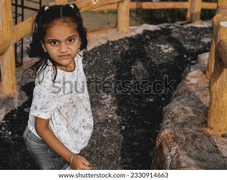 Little girl sitting on hill and walking around it. Cute and nice light present filter effect on portrait camera photo. Clear subject focus behind defocus background. Kid wearing black and white dress.