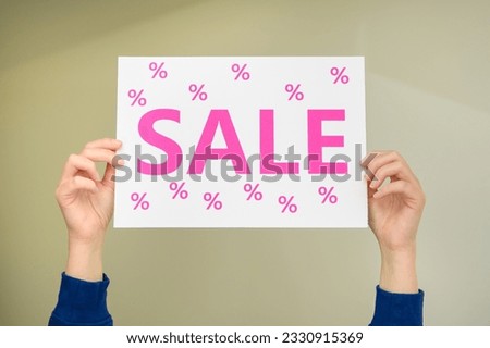 Card with pink sale inscription held in hands, palms up, signboard
