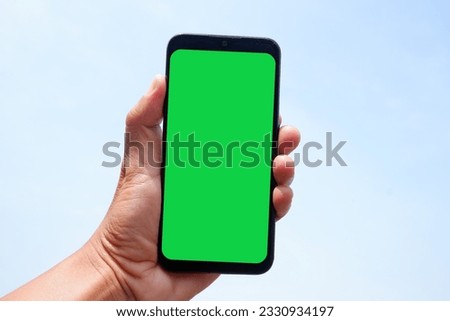 smartphone in hand against blue sky background