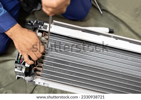 Technician is fixing or checking the evaporator system, troubleshooting air conditioning unit or dismantling for air conditioner fan coil unit cleaning,repair and maintenance,install air conditioner Royalty-Free Stock Photo #2330938721