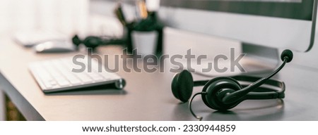 Panorama view of empty call center operator workspace, focused on headset. Representing corporate customer service support and telesales communication technology. Prodigy Royalty-Free Stock Photo #2330944859