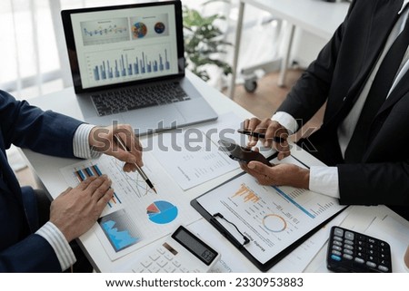 Business team and two colleagues discussing data from graph Financial charts and documents use mobile phones to contact negotiations. Planning on the office desk, startup business concept. Royalty-Free Stock Photo #2330953883