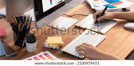 Graphic designer work on computer laptop and with graphic drawing pen while brainstorming unique design with professional graphic team in modern digital studio workplace. Panorama shot. Scrutinize Royalty-Free Stock Photo #2330959651