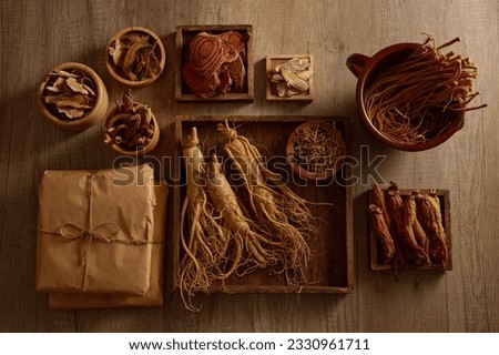 Many types of traditional chinese medicine are arranged inside some wooden trays and bowls on the table. For medicine advertising, photography traditional medicine content