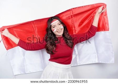 Happy smiling Indonesian woman holding Indonesia's flag to celebrate Indonesia Independence Day isolated over white background. Royalty-Free Stock Photo #2330961955