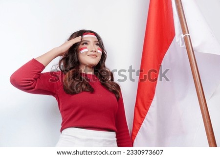 Indonesian woman give salute with proud gesture while holding Indonesia's flag. Indonesia's independence day concept.