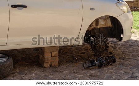 Backyard automotive repair job with vehicle balanced on bricks