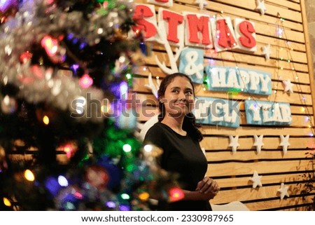 an asian woman in a christmas decoration full of dim colorful lights