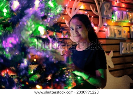an asian woman in a christmas decoration full of dim colorful lights