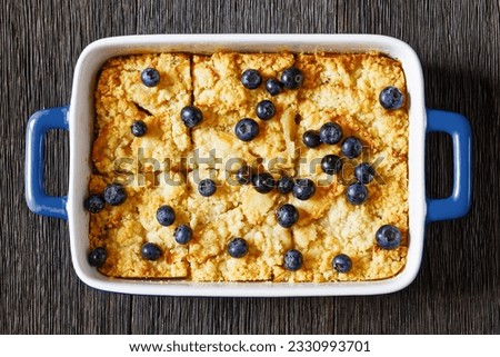 Homemade Apple Crumble with apples, cinnamon, spices, sweet  and buttery crumble and fresh blueberries sprinkled over top in baking dish on dark wooden table, flat lay, close-up