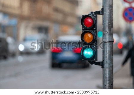 blurred view of city traffic with traffic lights, in the foreground a semaphore with a green light