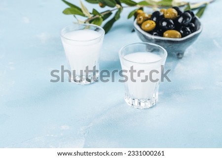 Traditional greek vodka ouzo and marinated olives on blue slate background. Copy space