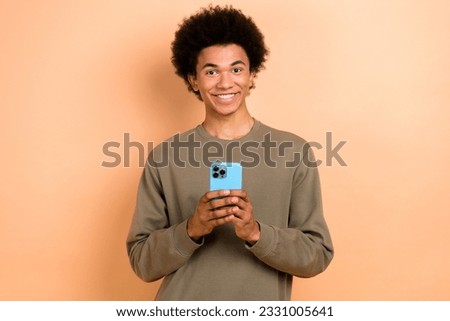 Photo of cheerful satisfied handsome blogger popular man hold smartphone wear pullover enjoy amazon black friday isolated on beige color background