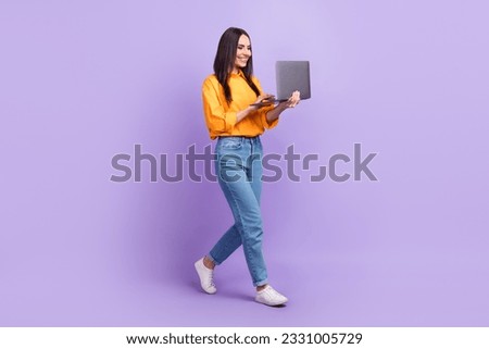 Full length photo of optimistic nice cute girl dressed yellow shirt pants look at laptop read email isolated on purple color background
