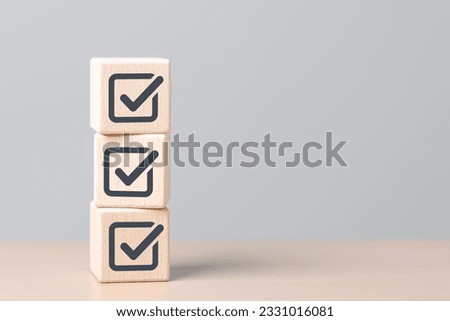 Check mark icons for jobs list on the face of wooden stacked blocks. Task lists, Checklist, Survey, Assessment, List, Confirm items, Double check, Quality Control. Goals achievement business success.  Royalty-Free Stock Photo #2331016081