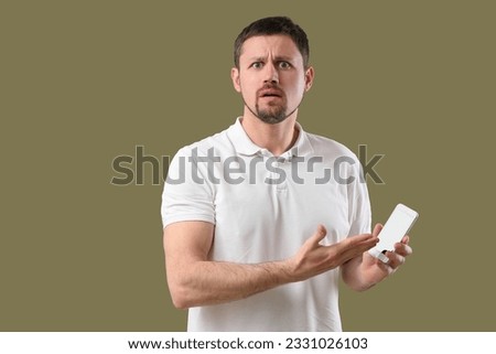 Shocked man with smartphone on color background Royalty-Free Stock Photo #2331026103