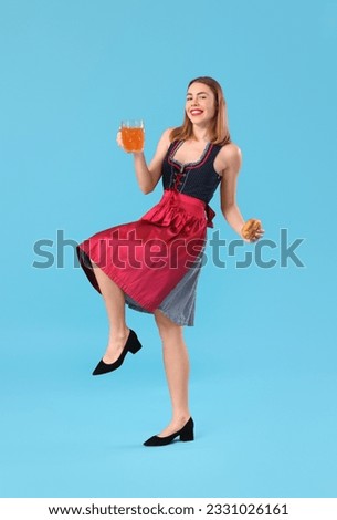 Beautiful Octoberfest waitress with beer and pretzel dancing on blue background