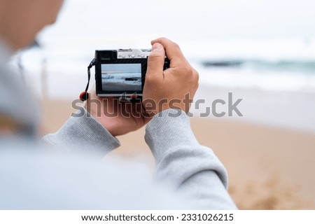 Traveller make photo using mirrorless camera in hand, travel blogger, Close up of mens hands holding mirrorless camera taking picture at ocean view