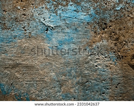 The texture of an old concrete wall painted over with strokes of blue and light brown paint. Photo.