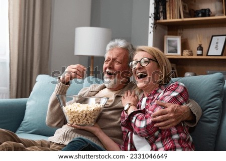 Old retired age couple watching TV at home, old mature couple cheering sport games competition together with laugh smile victory on sofa couch at living room home. Senior man and woman movie night. Royalty-Free Stock Photo #2331046649