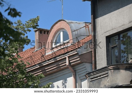 an arched skylight is installed on the sloping roof covered with clay tiles