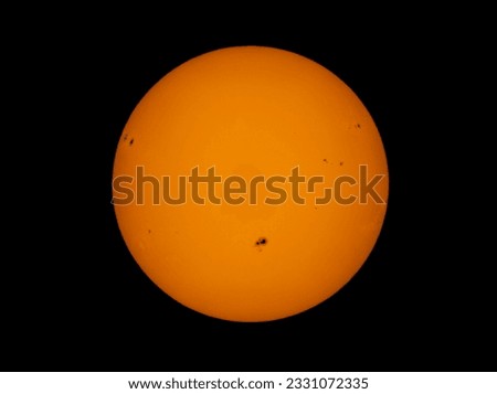 The orange coloured afternoon sun glowing with many sunspots using a homemade solar filter against a black background. Royalty-Free Stock Photo #2331072335