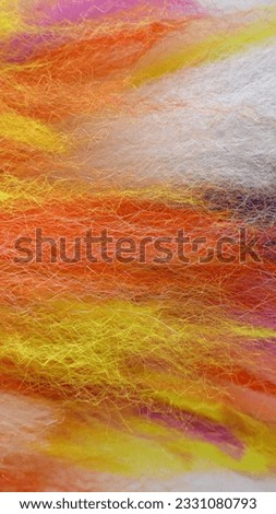 Vertical picture of fluffy wool-like threads in the colours orange, yellow, white and a bit of pink