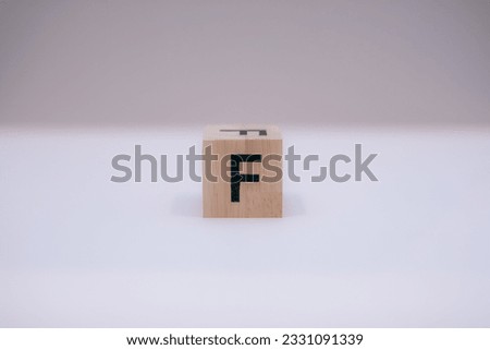 Wooden block written "F" with a white background
