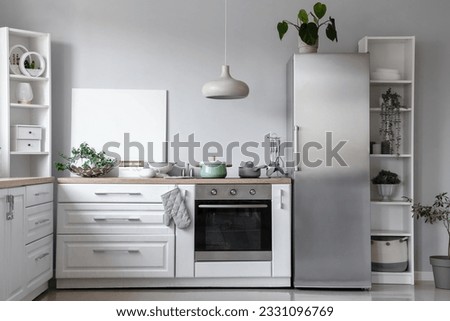 Interior of light kitchen with stylish fridge, counters and shelving units
