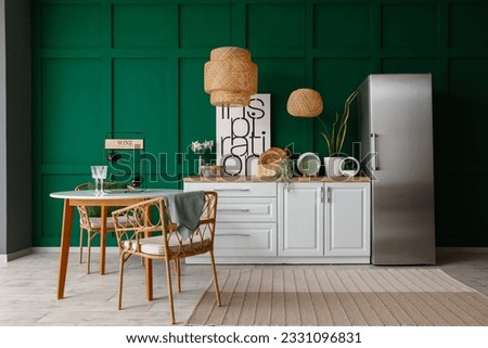 Interior of kitchen with stylish fridge, counters, lamps, table and chairs