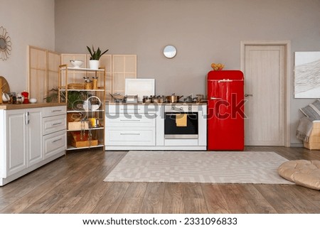 Interior of kitchen with red fridge, counters and shelving unit