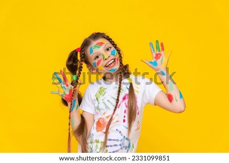 A child painted with multicolored paints. A young girl with painted palms. Creativity for schoolchildren. Drawing for children. Yellow isolated background. Royalty-Free Stock Photo #2331099851