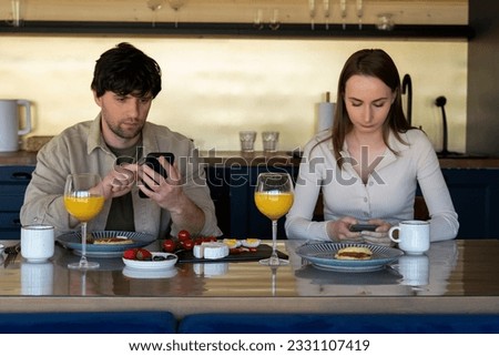 Young family drinks coffee and looks at smartphones. A young couple using smartphones ignore each other. use mobile apps or check social networks online. steam and technological concept Royalty-Free Stock Photo #2331107419